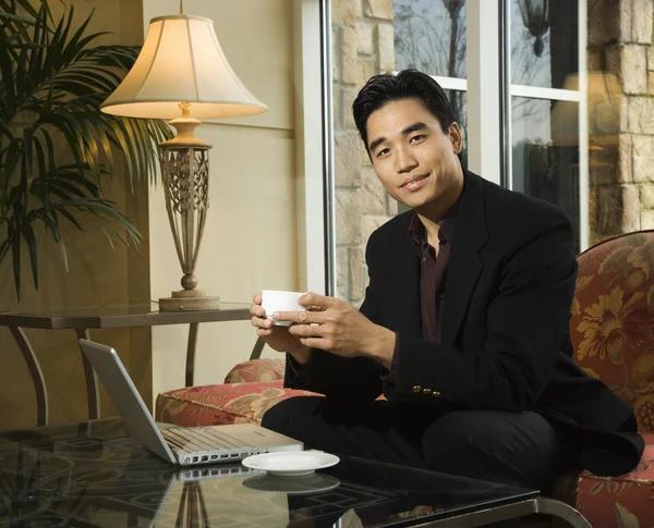 Νέος επιχειρηματίας στο lap-top που κατέχει ένα φλυτζάνι καφέ — Φωτογραφία Αρχείου