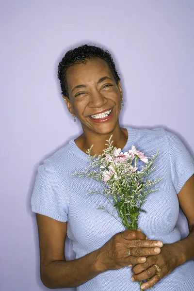 Smiling woman holding flowers. — Stock Photo, Image