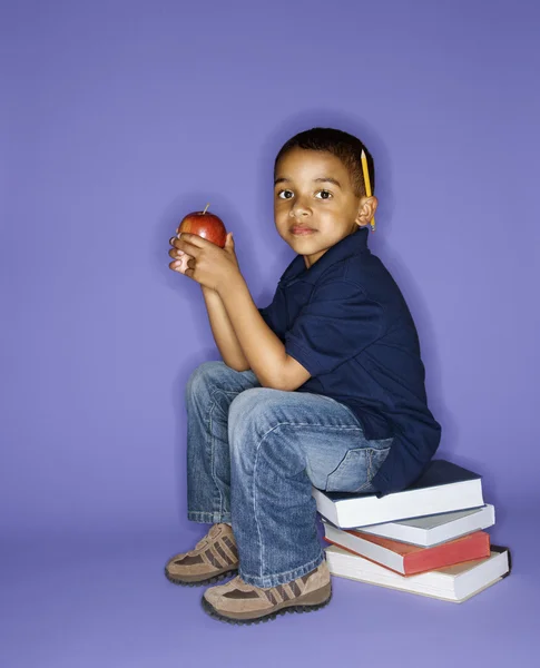 Chłopiec siedzi na książki. — Zdjęcie stockowe