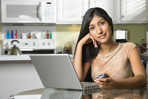 Jonge lachende vrouw met laptop en mobiele telefoon — Stockfoto