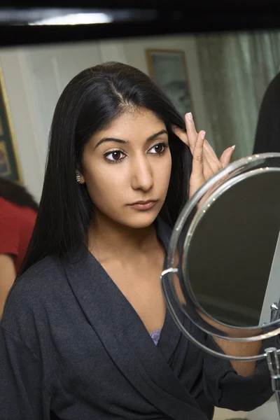 Mujer joven mirando en el espejo . — Foto de Stock