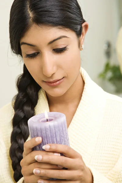Woman looking at lit candle. — Stock Photo, Image
