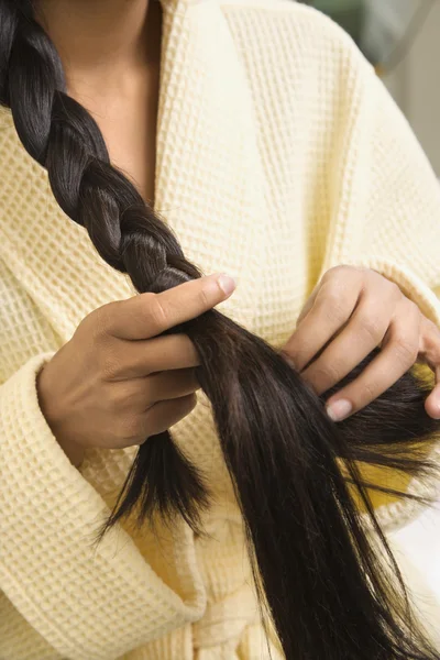 Mulher jovem trançando o cabelo . — Fotografia de Stock
