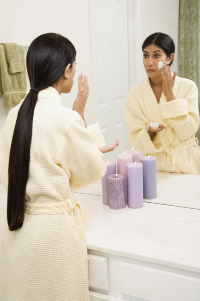 Mujer joven aplicando exfoliante facial . — Foto de Stock