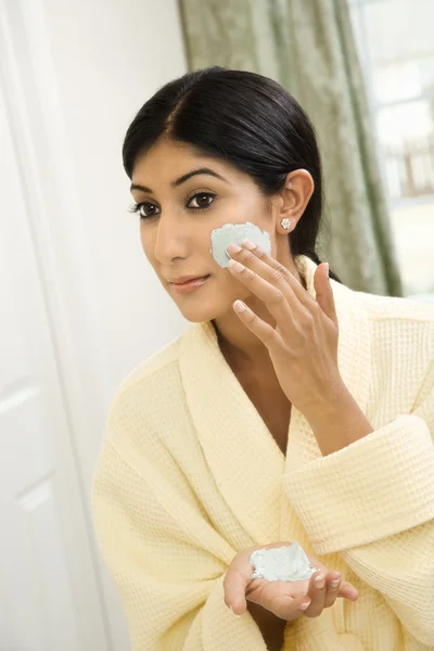 Jovem mulher aplicando esfoliação facial . — Fotografia de Stock