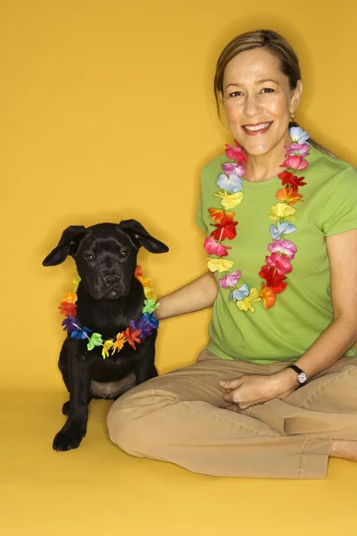 Vrouw met puppy dragen leis. — Stockfoto