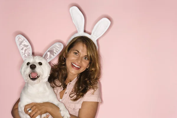 Жінка і білий собака в кролячих вухах . — стокове фото