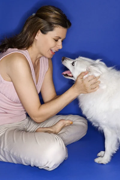 Frau streichelt weißen Hund. — Stockfoto