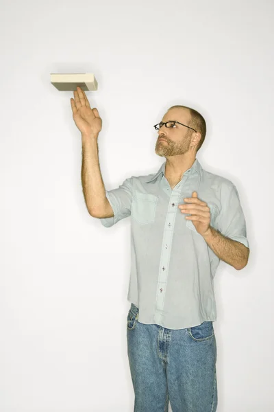 Man balancing book on finger. — Stock Photo, Image