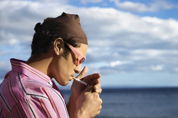 Giovane uomo sulla spiaggia che accende una sigaretta — Foto Stock