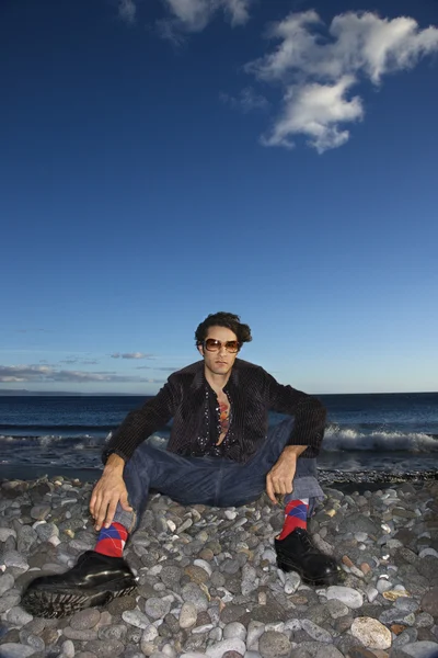 Modny mężczyzna siedzi na plaży. — Zdjęcie stockowe