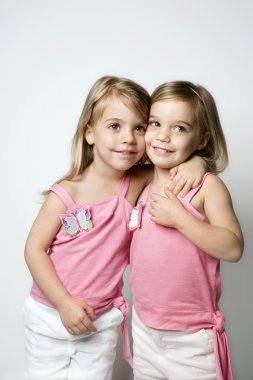 Girl child twin sisters embracing. clipart