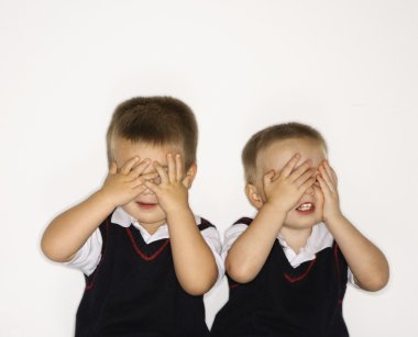 Male twins with hands over eyes. clipart