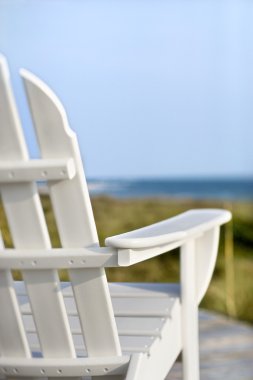 Adirondack chairs pointing toward ocean. clipart