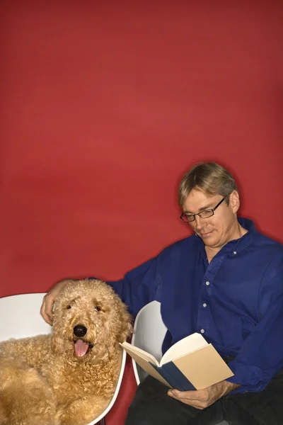 Man reading with goldendoodle dog. — Stock Photo, Image