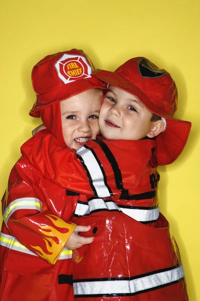 Zwillingsjungen als Feuerwehrmänner verkleidet. — Stockfoto