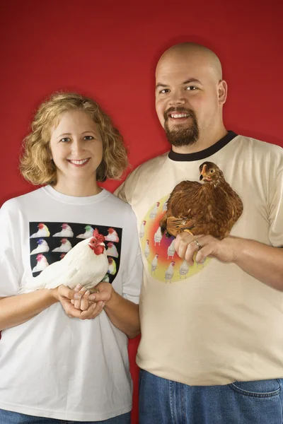 Smiling couple holding chickens. — Stock Photo, Image