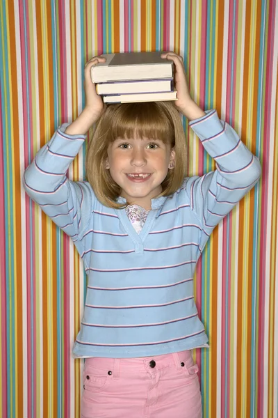 Mädchen balanciert Bücher auf dem Kopf. — Stockfoto