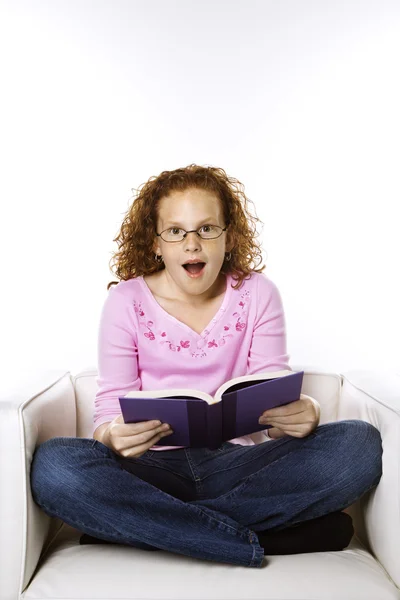 Dívka čtoucí knihu pohledu překvapený. — Stock fotografie