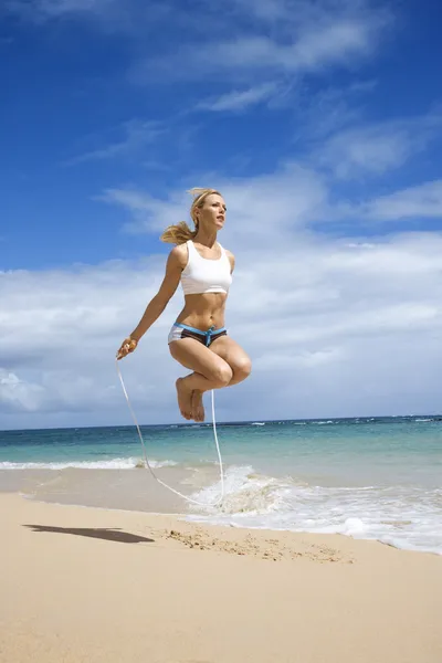 Mulher pulando corda na praia . — Fotografia de Stock