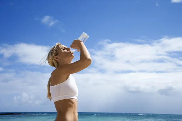 Femme eau potable sur la plage . — Photo