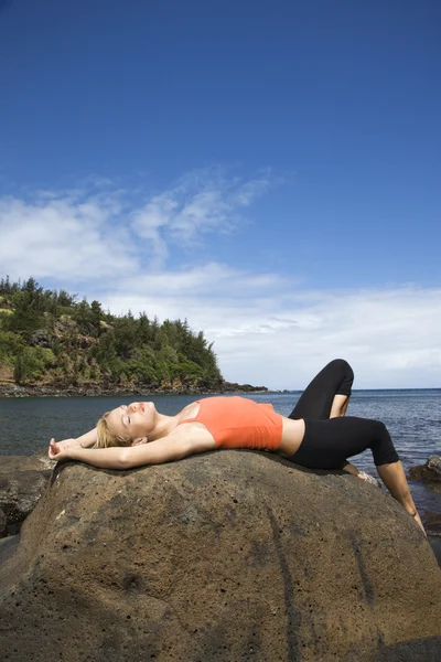 Aantrekkelijke jonge vrouw liggend op rock op strand — Stockfoto
