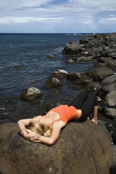 Ελκυστική νεαρή γυναίκα που βρίσκεται πάνω σε βράχο στην παραλία — Φωτογραφία Αρχείου