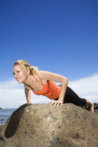 Femme faisant pousser vers le haut sur le rocher . — Photo