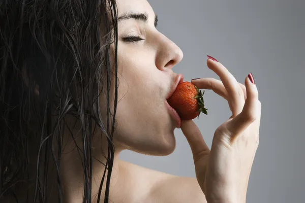 Frau beißt in Erdbeere. — Stockfoto