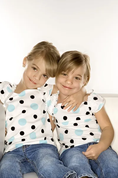 Meisje tweeling samen zitten. Stockfoto