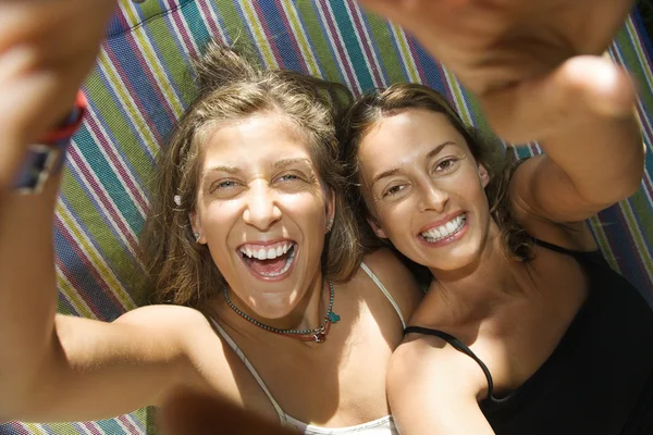 Vrouwen lachen in hangmat. Stockafbeelding