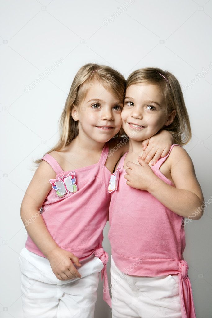 Girl child twin sisters embracing.