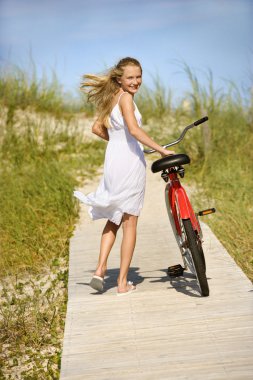 Girl Walking Bike on Boardwalk. clipart