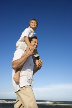 Dad carrying son on his shoulders. clipart