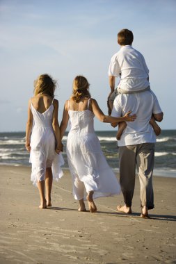 Family walking down beach. clipart