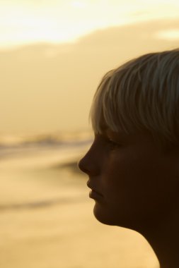 Boy on beach at sunset clipart