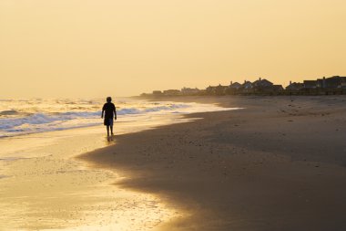 Boy walking on beach. clipart