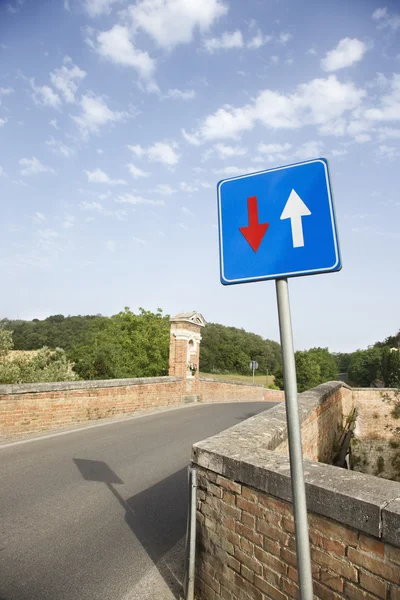 Estrada rural com sinal e parede de tijolo — Fotografia de Stock