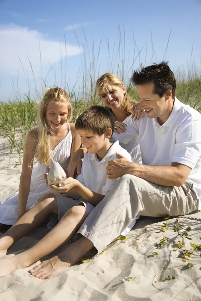 Rodina sedí na pláži. — Stock fotografie