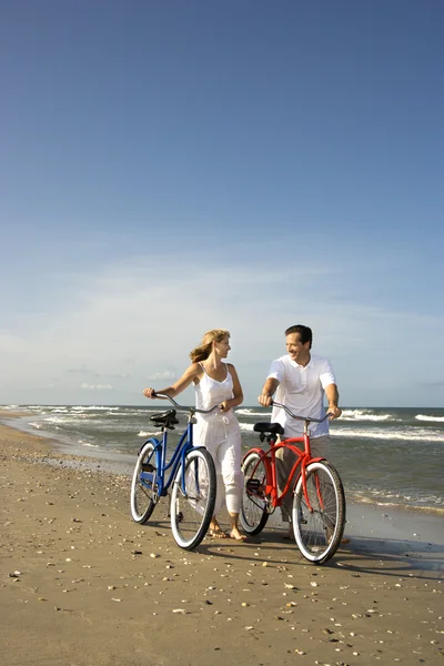 Paar mit Fahrrädern am Strand — Stockfoto