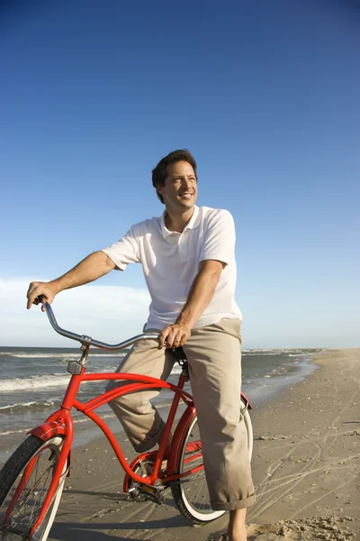ビーチに赤い自転車に乗る人. — ストック写真