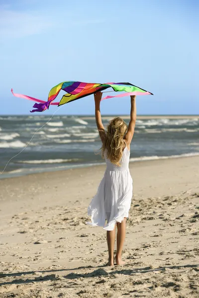 Mädchen hält Drachen am Strand. — Stockfoto
