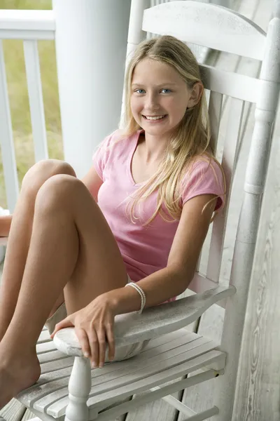 Meisje in schommelstoel op veranda. — Stockfoto
