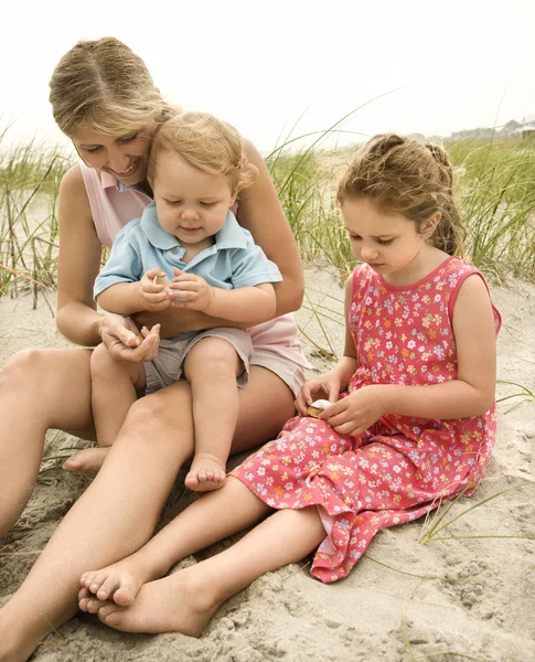 Mutter und Kinder betrachten Muscheln. — Stockfoto