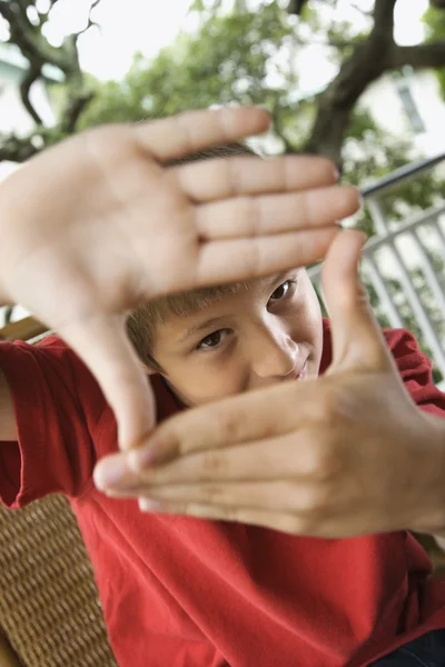Niño mirando a través de las manos — Foto de Stock