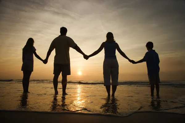 Οικογένεια, κρατώντας τα χέρια στην παραλία βλέποντας το ηλιοβασίλεμα — Φωτογραφία Αρχείου