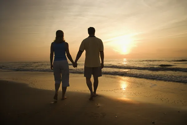 Gün batımında sahilde yürüyen çift. — Stok fotoğraf