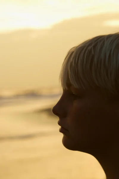 Chlapec na pláži při západu slunce — Stock fotografie