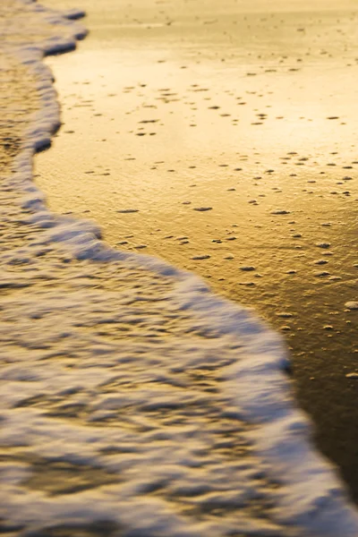 Vågorna läppning stranden i solnedgången. — Stockfoto