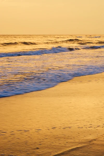 Hullámok átfedésben tengerparton naplementekor. — Stock Fotó